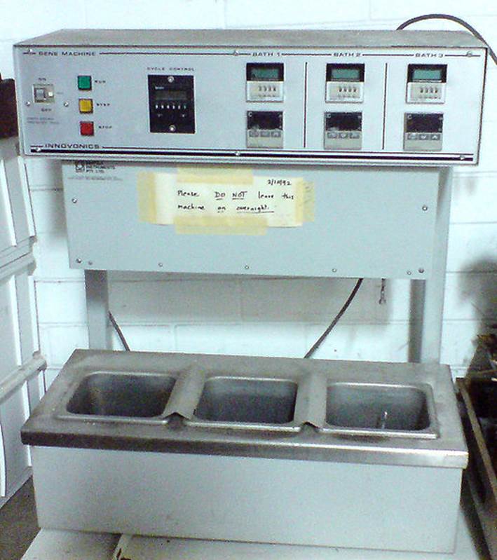 A metal machine with control panels and three sink-like compartments, labeled with 'BATH 1', 'BATH 2', and 'BATH 3'. A notice on the front reads 'Please DO NOT leave this machine on unattended'.